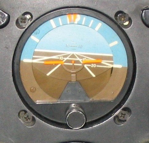 Foto real de um horizonte artificial no painel da aeronave.